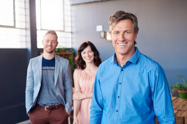 Businessman standing in office with colleagues — Stock Photo, Image