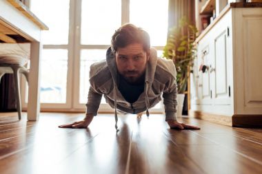 Genç adam onun daire katında planking egzersiz sırasında sırasında süzme spor giyim uygun