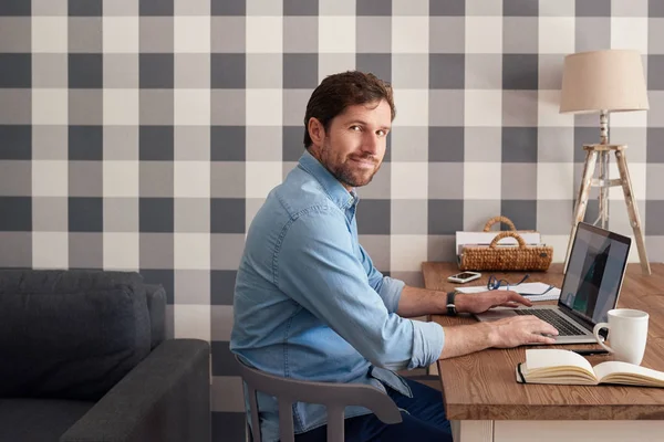 自信を持ってビジネスの所有者が自宅で一人で仕事しながら彼のリビング ルームのテーブルでノート パソコンでオンライン作業 — ストック写真