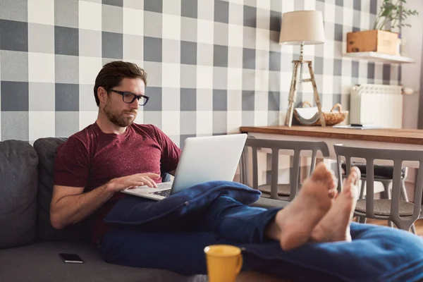 Ung Man Sitter Med Fötterna Hans Vardagsrum Soffa Hemma Surfa — Stockfoto