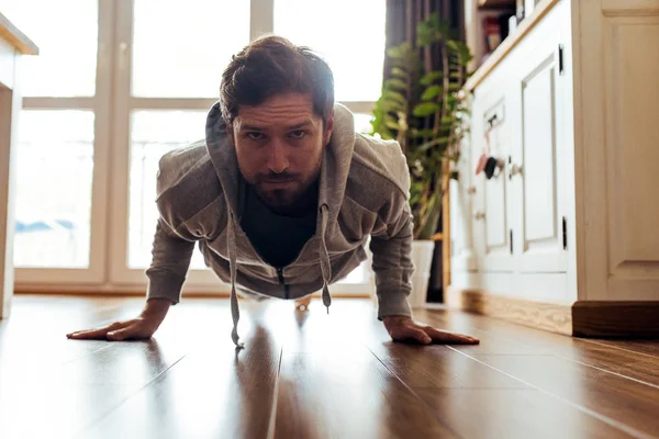 专注运动的男子在运动衫紧张 而地板上他的公寓在锻炼期间 — 图库照片