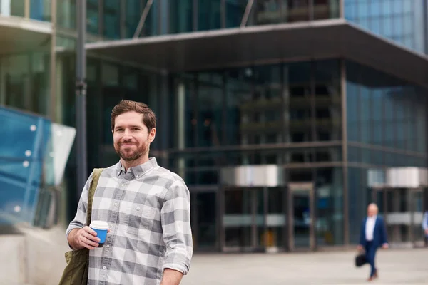 自信を持って若い男の街の建物の前に立ってコーヒーを飲むと笑顔カップ — ストック写真