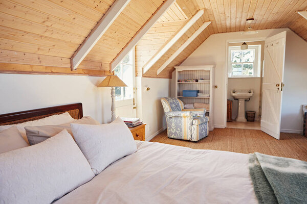 Interior of a comfortable master bedroom with an en suite bathroom in the loft of a contemporary residential home 