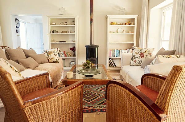 Interior of a country style living room with a sofa, chairs and fireplace in a bright residential home