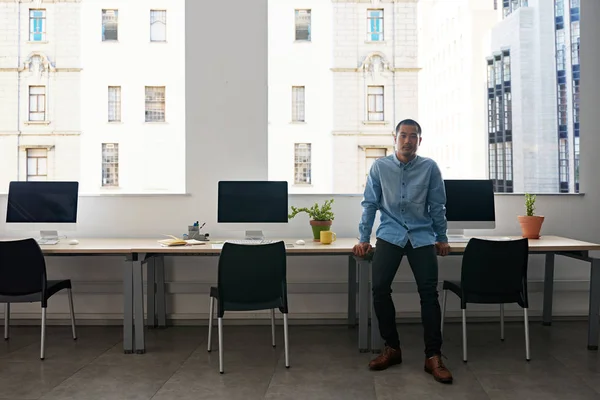 近代的なオフィスにコンピューターによってテーブルに寄りかかって自信を持って若いアジア人デザイナー — ストック写真