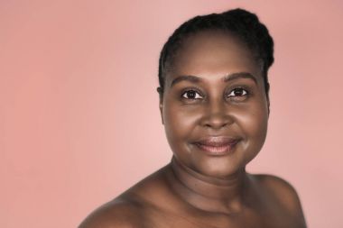 Arka plan renkli çiçek açan bir dahlia karşı ayakta mükemmel ten rengi ile boyutu Afrikalı kadın genç gülümseyen