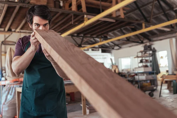 Joven Carpintero Usando Delantal Trabajando Solo Taller Examinando Hábilmente Tablón —  Fotos de Stock