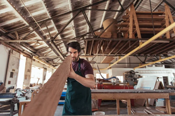 Joven Artesano Cualificado Que Usa Delantal Inspeccionando Tablón Madera Busca — Foto de Stock