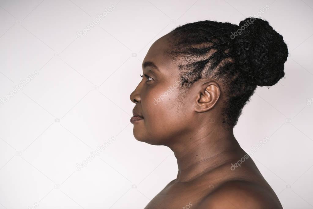 Profile of mature plus size African woman with beautiful skin standing against a white background