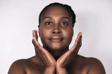 Artı boyutu Afrikalı kadın ile mükemmel bir cilt ayakta elleriyle yüzünü beyaz bir arka plan karşı çerçeveleme güzel