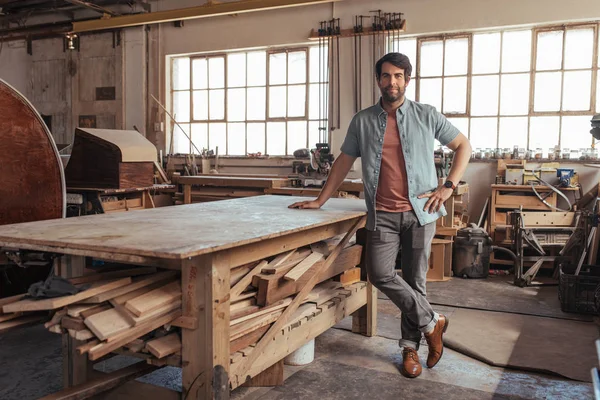 Retrato Joven Carpintero Confiado Pie Junto Banco Trabajo Lleno Madera — Foto de Stock