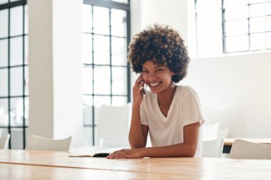 Tesadüfen gülümseyerek ve yalnız kampüste bir masada otururken ona cep telefonundan bir konuşmayı kıvırcık saçlı Genç Afrikalı kız öğrenci giyinmiş