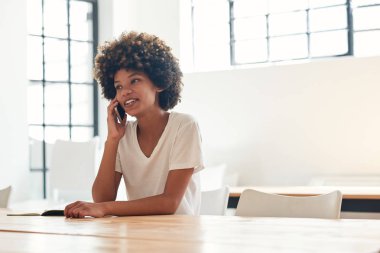 Tesadüfen gülümseyerek ve yalnız kampüste bir masada oturan süre onu cep telefonundan konuşuyor kıvırcık saçlı Genç Afrikalı kız öğrenci giyinmiş