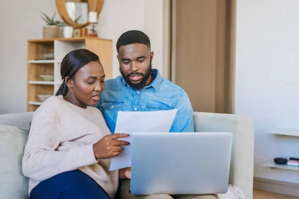 年轻的非洲裔美国人夫妇坐在客厅沙发上 一边上网一边用笔记本电脑付账 — 图库照片