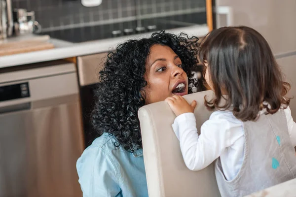 Sonriente Madre Sorprendiendo Adorable Hijita Sentada Una Silla Cocina Casa — Foto de Stock