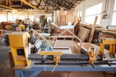 Büyük bir marangozluk atölyesinin içinde büyük bir sanayi tornası ve ahşap bir mobilya ve makine parçası.