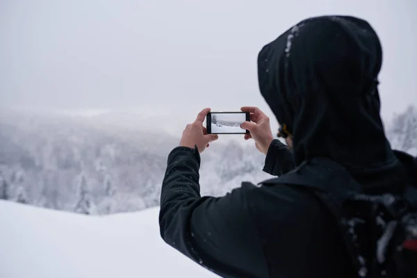 Молодой Человек Спортивном Снаряжении Фотографирует Зимний Пейзаж Мобильного Телефона Время — стоковое фото