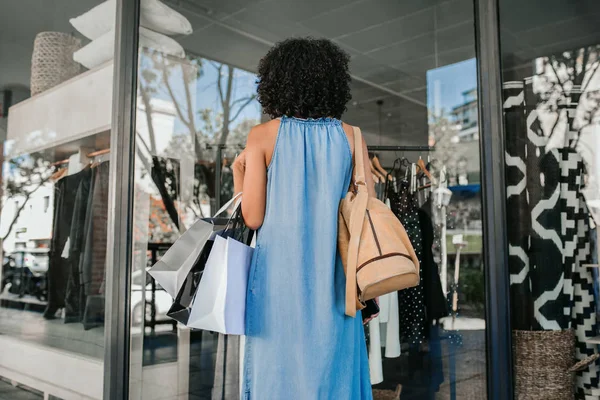 Mujer mirando en el escaparate de una tienda de ropa mientras va de compras —  Fotos de Stock