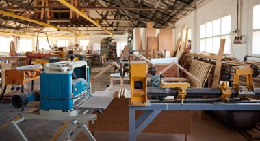 Industrial lathes, wood and other assorted machinery sitting on the floor in a large woodworking shop