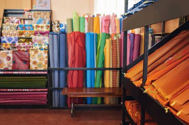 Colorful assortment of printed textiles on display on shelves and racks in a fabric shop