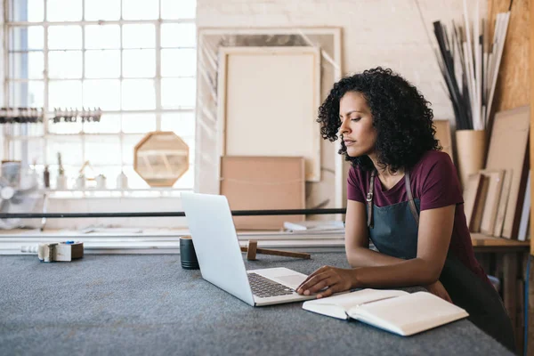 Młoda Kobieta Pracuje Online Laptopem Opierając Się Stół Warsztatowy Pracowni — Zdjęcie stockowe