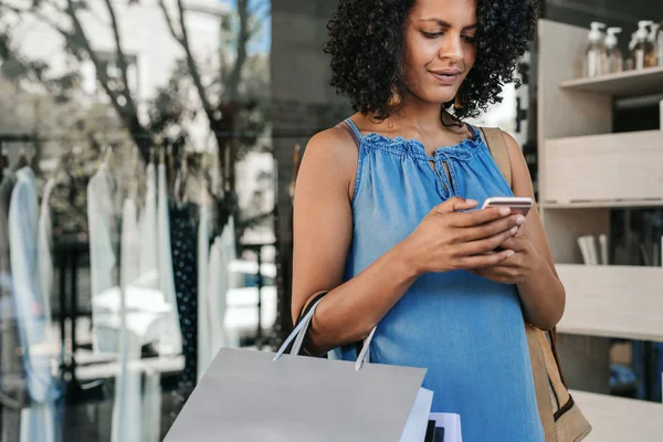 Egy Fiatal Táskákat Cipel Sms Küld Mobilján Miközben Ruhákat Vásárol — Stock Fotó