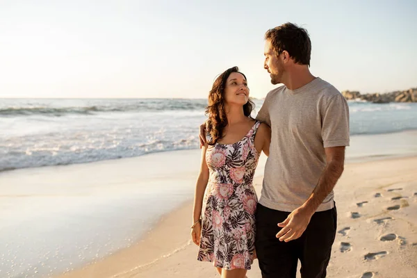 砂浜に沿って腕を組んで歩いている間 お互いを見て若いカップルを愛情 — ストック写真