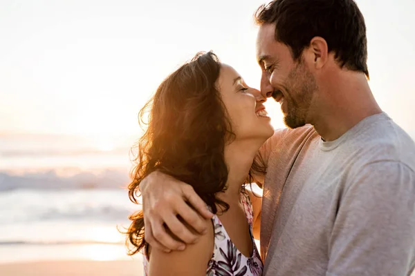 夕日の砂浜でお互いの腕の中で近くに立って若いカップルを愛情 — ストック写真