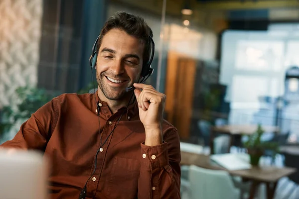 Mosolygó Üzletember Beszél Egy Ügyféllel Egy Fülhallgatón Keresztül Miközben Egy — Stock Fotó