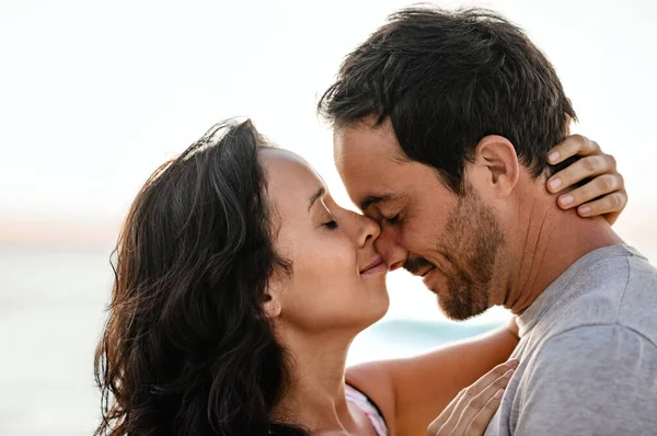 Loving young couple standing in each other\'s arms with their eyes closed on a beach at sunset