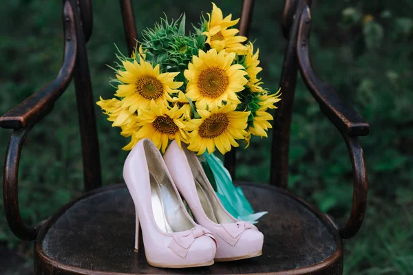 Belle scarpe da sposa con tacchi alti e un mazzo di girasoli — Foto Stock