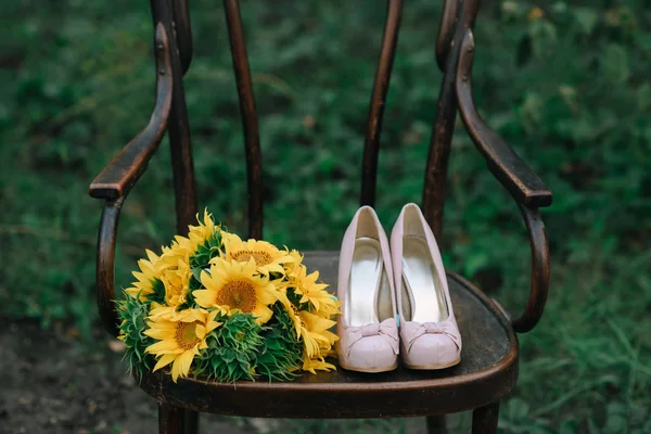 Schöne Hochzeitsschuhe mit High Heels und einem Strauß Sonnenblumen — Stockfoto