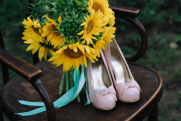 Belle scarpe da sposa con tacchi alti e un mazzo di girasoli — Foto Stock