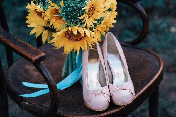 Belle scarpe da sposa con tacchi alti e un mazzo di girasoli — Foto Stock