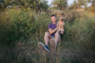 Yakışıklı genç adam tutarak ve yorkshire terrier köpek sarılarak