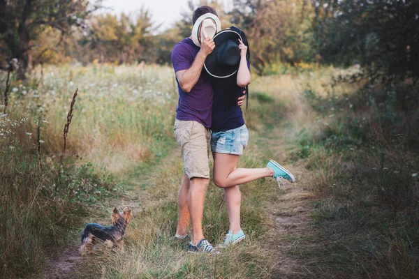 Genç çift küçük köpek ile yorkshire terrier giymiş t-shirt ve şapka kucaklayan ve yolda iyi eğlenceler — Stok fotoğraf