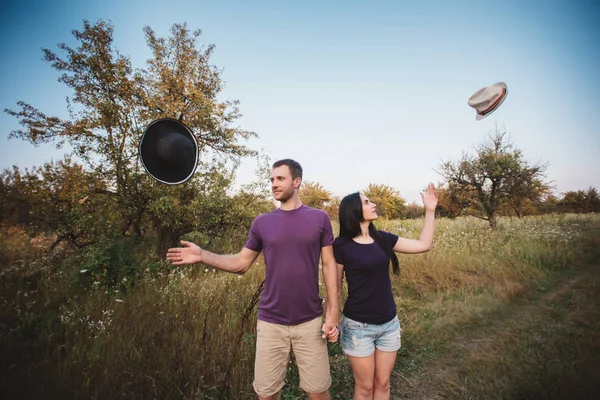 Молода пара кидає капелюхи в повітря — стокове фото