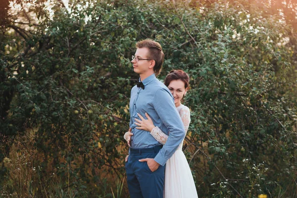 Sunshine portrait of happy bride and groom outdoor in nature location at sunset — Stock Photo, Image