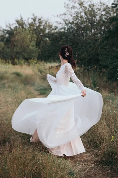 Yong mariée filant dans une robe blanche sur la rive sur la nature — Photo