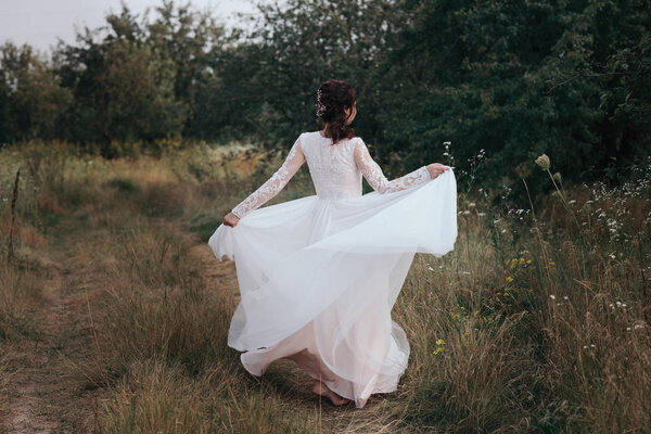 Yong bride spinning in a white dress on the bank on nature.Dress develops in the wind. Happy bride in a wedding dress is spinning.