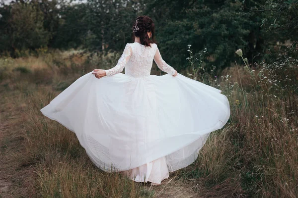 Yong Braut dreht sich im weißen Kleid am Ufer der Natur — Stockfoto