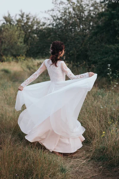 Yong novia girando en un vestido blanco en la orilla de la naturaleza — Foto de Stock