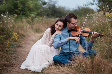 Kemancı ve beyaz elbiseli kadın, genç adam arka plan doğa keman çalış,