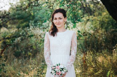 Beyaz elbiseli poz makyaj ve saç modeli ile genç güzel gelin