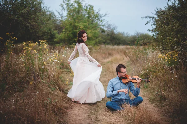 Violinist and woman in white dress , young man plays on the violin the background nature,