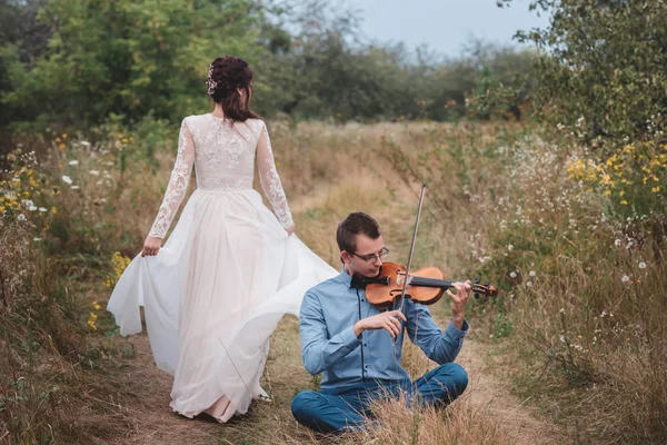 Violinista e donna in abito bianco, giovane suona sul violino la natura di sfondo , — Foto Stock