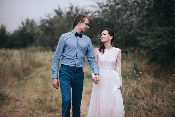 Just married loving hipster couple in wedding dress and suit on a green field in the woods. — Stock Photo, Image