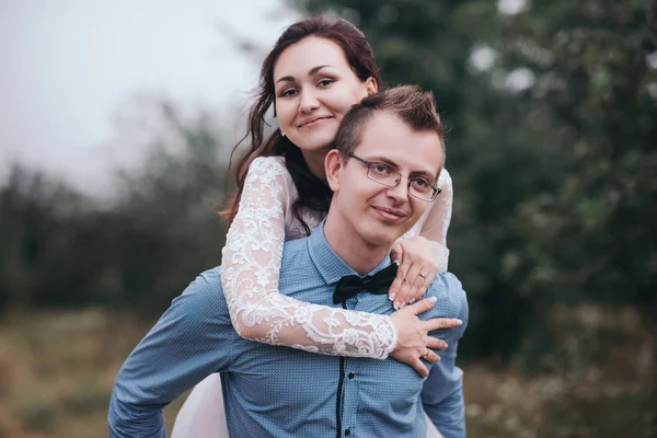 Novio lleva novia en sus brazos en la naturaleza en la luz del atardecer —  Fotos de Stock