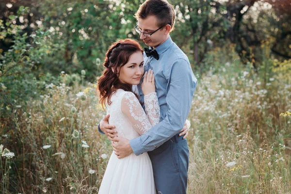 Juste marié aimant couple hipster en robe de mariée et costume sur un champ vert dans les bois. — Photo