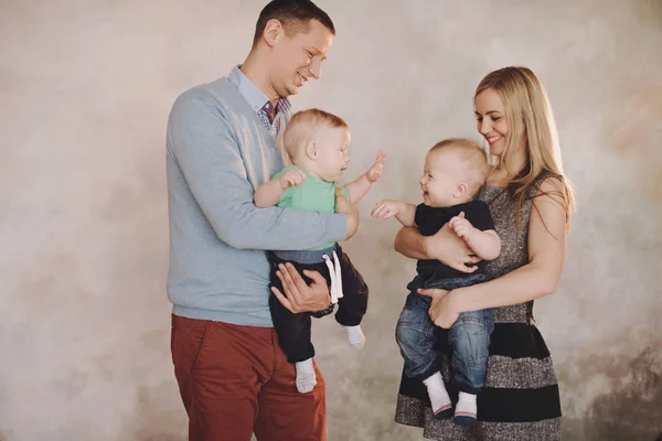 Vater und Mutter spielen mit zwei kleinen Söhnen. Zwei kleine Jungen, Geschwister Zwillinge und Eltern haben Spaß — Stockfoto